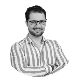 Black-and-white portrait of a bearded man in glasses, arms crossed, wearing a striped shirt