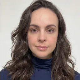 Portrait of a woman with long wavy brown hair wearing a navy turtleneck